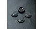 Four small black circular rubber shock seals arranged on a textured black surface.