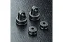 Four black plastic RC shock absorber caps, including two top caps with mounting eyes and two bottom caps, arranged on a textured black surface.