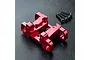 A red anodized aluminium upper suspension arm mount for an RC car, shown with four black mounting screws on a textured black surface.