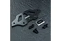 MST carbon fibre lower bumper plate with mounting screws and a small MST logo sticker on a dark textured surface.