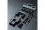 MST RRX conversion kit parts including molded plastic chassis components, screws, spacers, and washers arranged on a dark textured surface.