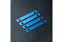 Four blue anodized metal suspension mount spacers arranged diagonally on a black textured surface.