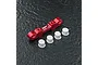 A red anodized aluminium MST suspension arm mount with four white plastic suspension inserts on a dark textured surface.