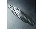 A top-down view of an MST lightweight carbon fibre RC car chassis plate featuring a complex cutout design and a woven carbon fiber texture.