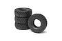 A set of four black Axial Nitto Trail Grappler RC crawler tyres stacked and arranged on a white background.