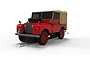 A 1/32 scale Scalextric Land Rover Series 1 slot car in poppy red with a tan soft top roof, positioned on a slot car track.