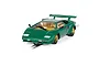 A 1/32 scale Scalextric Lamborghini Countach slot car in green with gold wheels, positioned on a piece of slot car track against a white background.