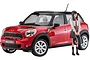 A 1/24 scale plastic model kit of a red Mini Cooper S Countryman All4 with a school girl figurine standing beside it.