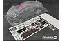 A clear, unpainted Bittydesign P-GT3R 1/10 scale RC car body shell with a decal sheet and small hardware bag on a dark surface.