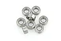 A cluster of eight small metal shielded ball bearings arranged on a white background.