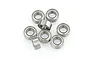 A cluster of eight small metal shielded ball bearings arranged on a white background.