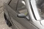 A close-up view of a black unpainted side door mirror mounted on a metallic grey 1/10 scale RC car body shell.