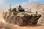 Box art illustration of a VBM Freccia armoured fighting vehicle in a desert landscape, featuring a camouflage paint scheme and eight wheels.