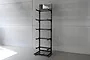 A black Koswork 5-layer metal display stand standing against a grey concrete wall.